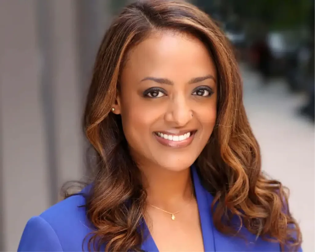 Professional corporate headshot of a smiling woman in a blue blazer and gold necklace, taken by Gorn Photo in NYC.