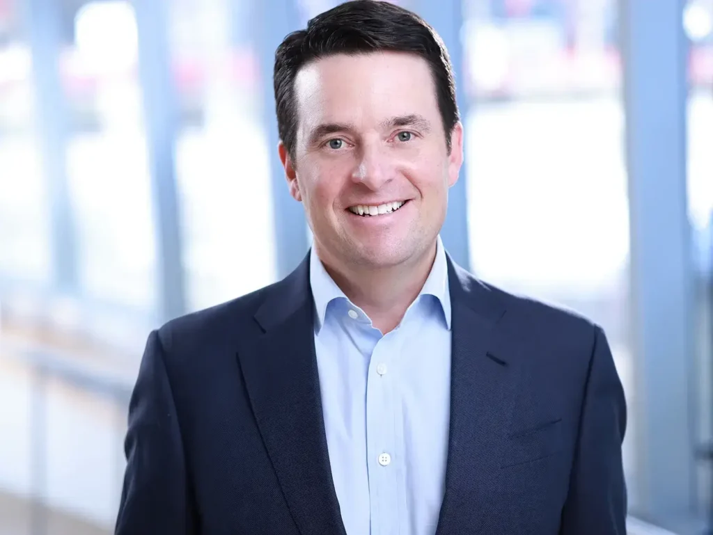Business professional posing for corporate headshots wearing a navy blazer and light blue shirt
