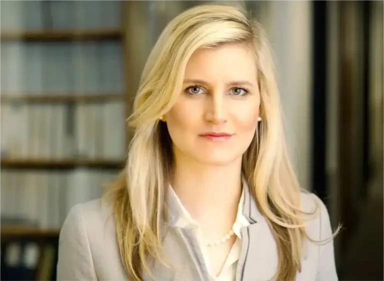 Professional blonde woman in a grey blazer and pearl necklace posing for corporate headshots for finance industry professionals.